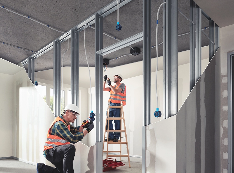 Zwei Männer in orangen Arbeitswesten arbeiten im Innenbereich des Bauprojekts SPOT in Amsterdam (Foto)