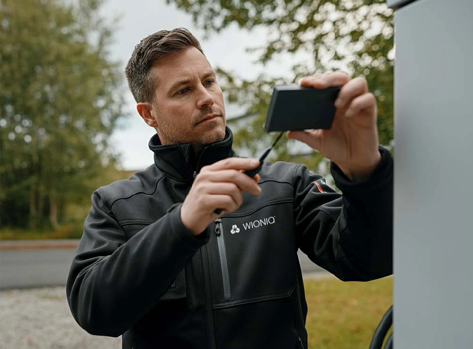 Mann in Arbeitskleidung bedient ein Handgerät (Foto)