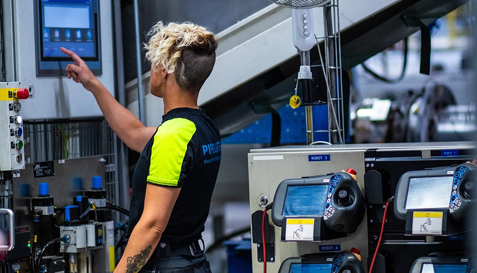 Person mit T-Shirt, auf dem hinten ‚Pipelife‘ steht, bedient eine Maschine in der Produktion (Foto)